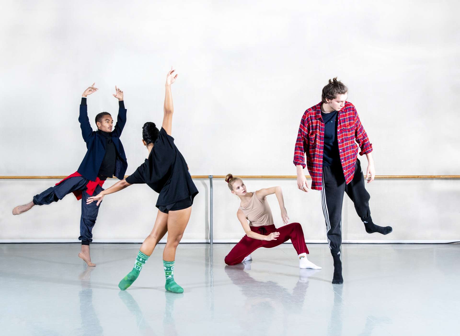 Quatre jeunes danseurs et danseuses répètent leur chorégraphie en tenue décontractée. 